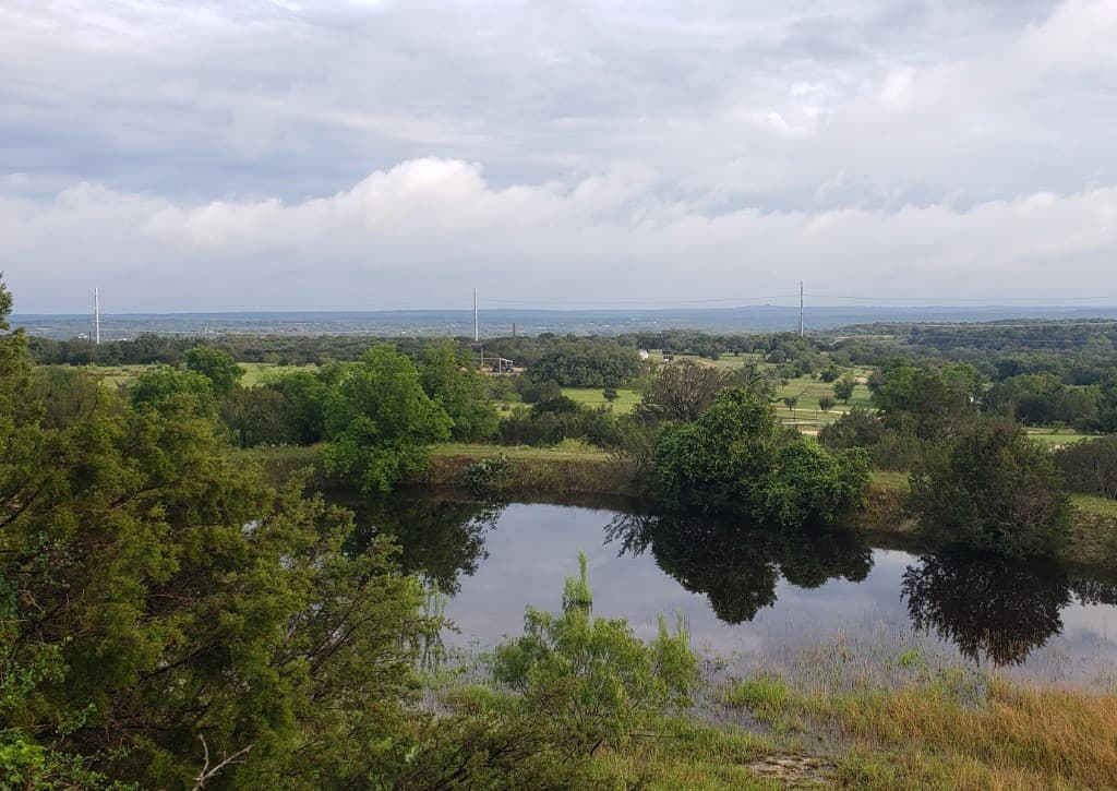 Texas Hill Country landscape — pond, trees, and open sky at Purdy Poodles